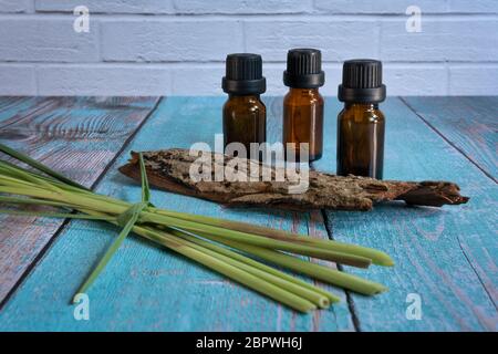 Ätherische Ölflaschen mit Zitronengras und etwas Holz auf Holztisch, horizontal geschossen Stockfoto