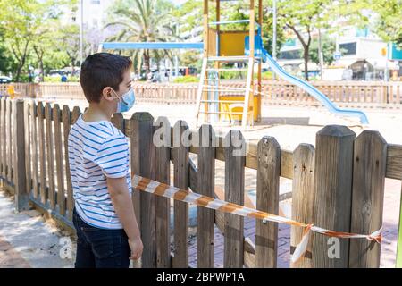 Trauriger Junge vor einem geschlossenen Spielplatz Stockfoto