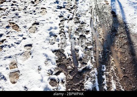 Draufsicht auf nassen schmutzigen Weg mit Schnee nach dem letzten Schneefall im Stadtpark am sonnigen Frühlingstag bedeckt Stockfoto