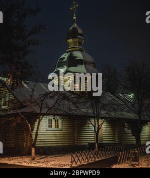 Orthodoxer Baum Russische Kirche mit Schnee bedeckt. Holzkirche mit Lichtern und beleuchteten Kreuzen auf den Gipfeln am heiligabend. Weihnachtsabend nahe Stockfoto