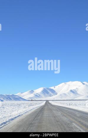 Die winterliche Schneelandschaft vom Lake Tekapo nach Christchurch. Die Fahrt führt durch mehrere Städte und entlang Ackerland dann die Bergblick. Stockfoto