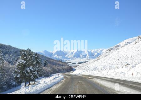 Die winterliche Schneelandschaft vom Lake Tekapo nach Christchurch. Die Fahrt führt durch mehrere Städte und entlang Ackerland dann die Bergblick. Stockfoto