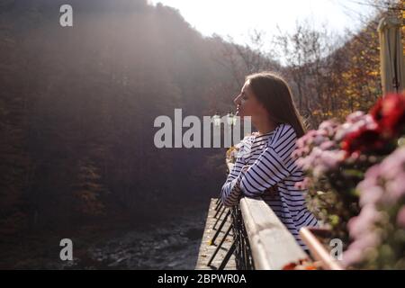 Junge schöne Frau genießt den Blick auf den Fluss auf der Terrasse eines Cafés an einem sonnigen Herbsttag. Selektive Fokus Stockfoto