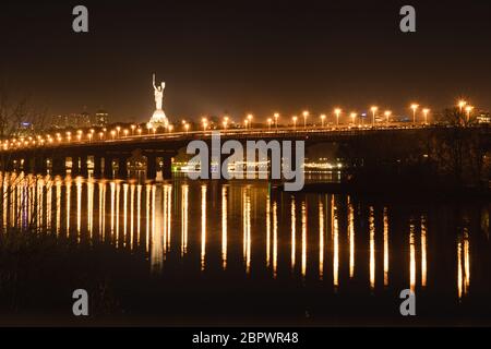 Nachtansicht der Brücke über den breiten Fluss Dnipro in Kiew auf einer langen Belichtung Stockfoto