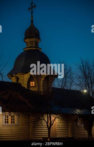 Holzkirche mit Lichtern und beleuchteten Kreuzen auf den Gipfeln am heiligabend. Weihnachtsabend in der Nähe der christlichen Kirche, geistlicher Moment. Stockfoto