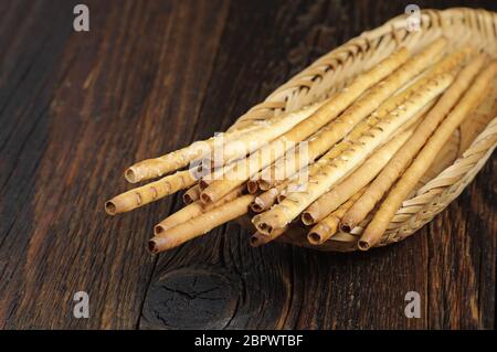 Salziges Brot klebt in Korbteller auf dunklem Holztisch Stockfoto