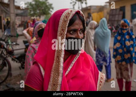 Indische Frauen warten auf kostenlose Nahrung in der Region Mustafabad, die kürzlich von Unruhen betroffen war, als das Land seine Lockdown-Beschränkung am 14. Mai 2020 in Neu-Delhi, Indien, lockert. Die Region Mustafabad gehörte zu den am schlimmsten betroffenen Gebieten, als im Februar in Indiens Hauptstadt Unruhen ausbrachen, weil ein umstrittenes Gesetz zur Änderung der Staatsbürgerschaft von der Regierung der Bharatiya Janata Partei verabschiedet wurde. Mehrere Familien, die aufgrund von Brandstiftung durch Randalierer obdachlos waren, kümmern sich nun um sich selbst inmitten einer landesweiten Lockdown, die von der Regierung auferlegt wurde, um die Ausbreitung des Coronavirus im Land einzudämmen. Zoll Stockfoto