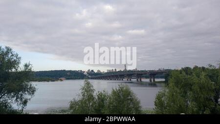 Breiter Fluss Dnjeper mit einer Brücke nach Sonnenaufgang mit schönen Wolken Stockfoto