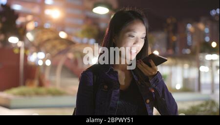 Frau, die im Freien eine Audionachricht auf dem Smartphone sendet Stockfoto