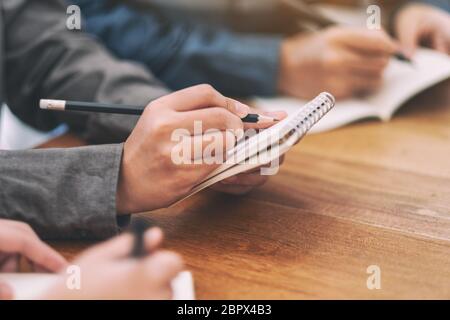 Nahaufnahme Bild der Hände halten und schreiben auf leere Notizbuch auf Holztisch Stockfoto