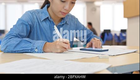 Frau schreibt mit Handy zu Hause auf das Papier Stockfoto