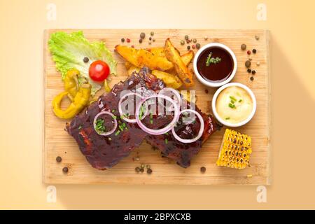 Glasierte Rippchen mit Gemüse auf einem Holzbrett serviert. Ansicht von oben. Essen von oben Stockfoto