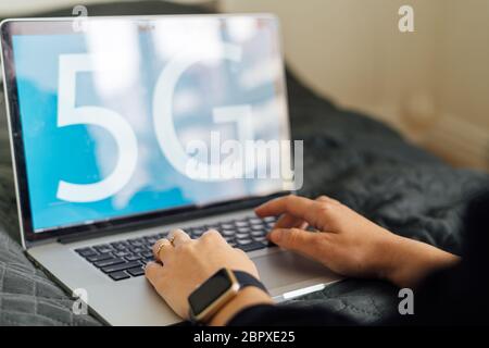 Blauer Hintergrund mit 5G-Zeichen auf Laptop und Arbeitskraft. Schnelles mobiles Netzwerk. Evolution in der Technologie Stockfoto
