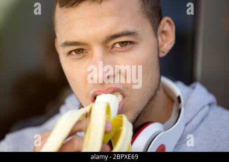 Junge latin Mann essen Bananen Obst runner Winter laufen sport training Fitness im Freien Stockfoto