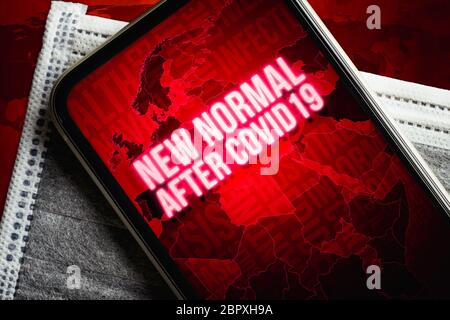 Die neue normale nach Covid-19 Hintergrundkonzept. Ein Smartphone mit neuer Normalität nach covid19 Nachricht mit Weltkarte auf der medizinischen Gesichtsmaske auf Grunge Stockfoto