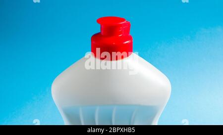 Weiße Plastikflasche mit Spülmittel, Bleichmittel oder Weichspüler auf blauem Hintergrund. Flüssiges Waschpulver. Das Konzept der Reinigung Stockfoto
