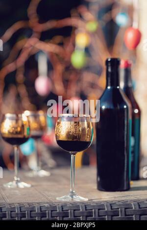 Flasche Wein, Glas und Ostereier im verschwommenen Hintergrund. Frühling Ostern Konzept. Stockfoto