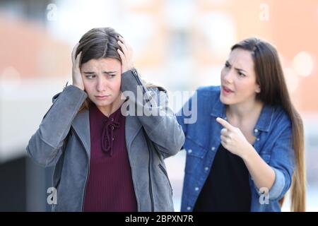 Böse Mädchen wirft ihr trauriger Freund, die Ohren zu Fuß auf der Straße Stockfoto
