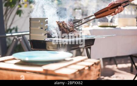 Chefkoch Grill t-bone Steak am Grill sonntag Mittagessen im Freien - Mann Kochen Fleisch für eine Familie grillmahlzeit draußen im Garten - Summe Lifestyle und Foo Stockfoto