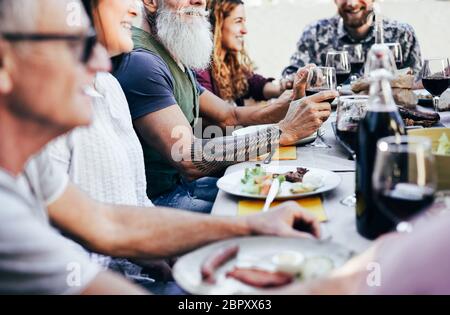 Glückliche Familie Essen und Wein trinken beim Barbecue Mahlzeit auf der Terrasse im Freien - Reife und junge Leute, die Spaß am bbq sonntag Mittagessen - Essen und Summe Stockfoto