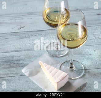 Zwei Gläser Weißwein mit Brie auf der hölzernen Hintergrund Stockfoto