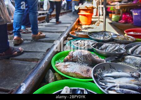 Verkauf von Speisen auf der Maeklong Railway Markt in Thailand. Stockfoto