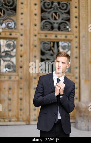 Hübscher Bräutigam steht neben einer Holztür. Stockfoto