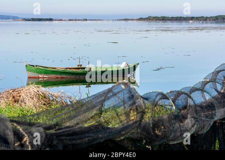 Panorama der Lagune in der Morgendämmerung in Sardinien und vor dem Hintergrund der rosa Flamingos. Im Vordergrund ein altes Holzboot. Stockfoto