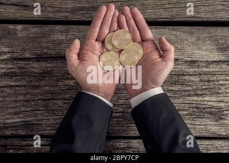 Draufsicht eines Geschäftsmannes in schwarzem Anzug mit goldenen Bitcoins in seiner Handfläche, Retro-Effekt verblichenen Look. Stockfoto