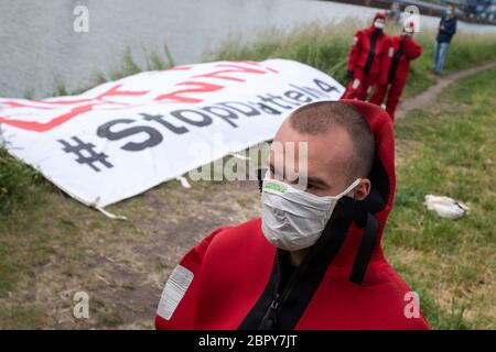 Datteln, Deutschland. Mai 2020. Greenpeace-Aktivisten in roten Neoprenanzügen stehen vor dem Kohlekraftwerk Datteln 4 und schwammen dann mit einem Banner im angrenzenden Dortmund-Ems-Kanal. Das Kohlekraftwerk im nördlichen Ruhrgebiet ist zum Symbol der energiepolitischen Debatte der Bundesregierung geworden. Das Kraftwerk des Düsseldorfer Energieunternehmens Uniper soll im Sommer endgültig ans Netz gehen. Der Betreiber Uniper hat eine Online-Einladung zu seiner Hauptversammlung am 20.05.2020 erteilt. Quelle: Bernd Thissen/dpa/Alamy Live News Stockfoto