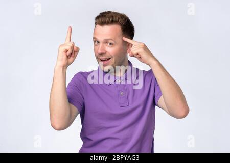 Reifer europäischer Mann hält Finger auf Tempel, er hat eine tolle Idee erzeugt und hatte den besten Plan, was jetzt zu tun. Studioaufnahme Stockfoto