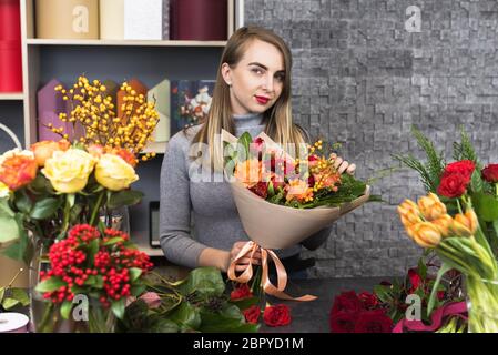 Mädchen sammelt einen Blumenstrauß verschiedener Blumen. Kleine Unternehmen. Stockfoto