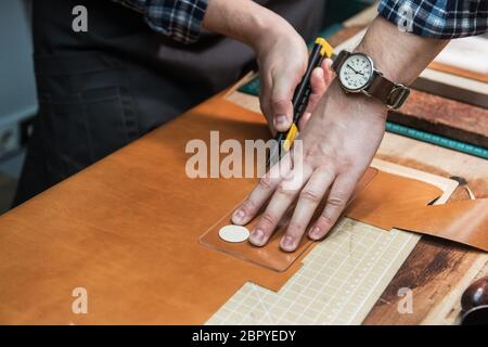 Mann bei der Arbeit mit Leder Textil bei einem Workshop. Craftman schneiden Leder. Konzept der Handarbeit Handwerk Herstellung von Lederwaren. Stockfoto