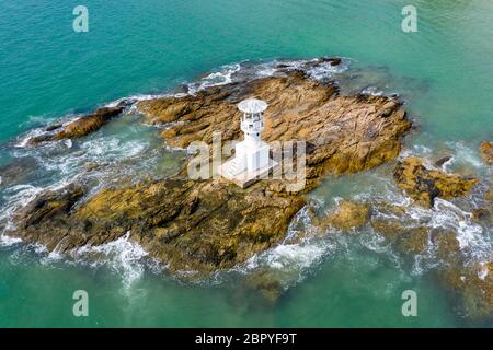 Drone-Ansicht eines kleinen Offshore-Leuchtturms auf einer kleinen, felsigen Insel Stockfoto