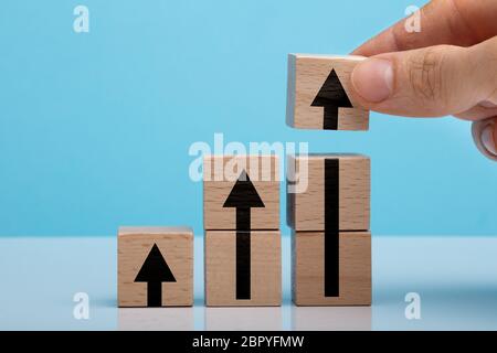 Des Menschen Hand Pfeil Holzklotz auf weißen Tisch vor blauem Hintergrund Stockfoto