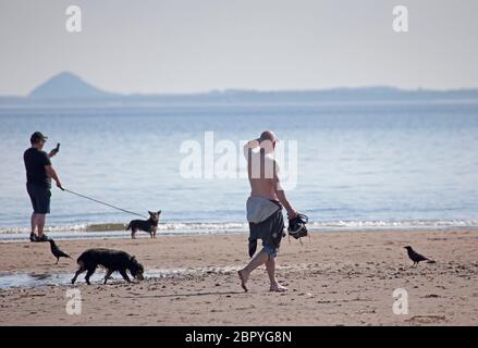 Portobello.Edinburgh, Schottland, Großbritannien. 20 Mai 2020. Ruhiger Start heiß sonnig und 18 Grad Celsius vor 10 Uhr.zwei Hundewanderer an der Küste mit Berwick Law im Hintergrund. Stockfoto