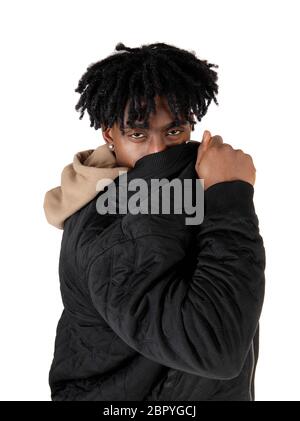 Eine afrikanische amerikanische Mann im Studio sein Gesicht hinter seine Jacke in die Kamera schaut, auf weißem Hintergrund Stockfoto