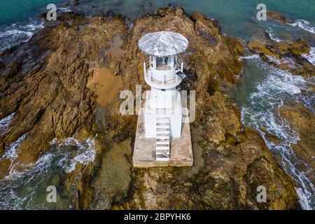 Drone-Ansicht eines kleinen Offshore-Leuchtturms auf einer kleinen, felsigen Insel Stockfoto