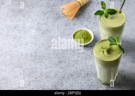 Zwei Gläser Dalgona Iced Matcha Tee und Zutaten auf grauem Hintergrund. Kopierbereich. Blick von oben. Stockfoto