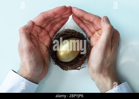 Eine erhöhte Ansicht der Geschäftsmann schützende Hand goldene Ei im Nest Stockfoto