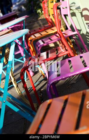 Bunte Metalltische und Stühle außerhalb eines Cafés in der Sonne, Stockfoto