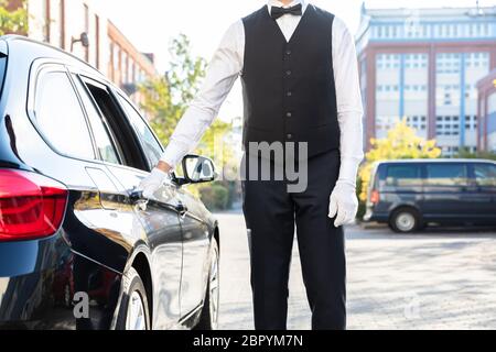 Der Parkservice Hand Öffnen schwarzes Auto Tür auf der Straße Stockfoto