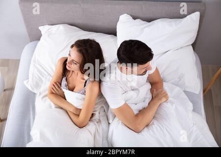 Blick von oben auf die verzweifelten Ehepaar Rücken an Rücken auf dem Bett Stockfoto