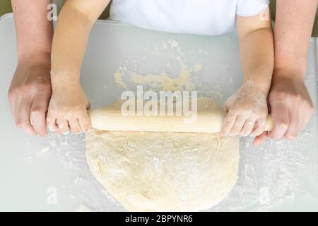 Glückliche Familie in der Küche. Papa und Tochter Rollen den Teig mit einem Nudelholz aus. Urlaub und Familie Freizeitkonzept. Stockfoto