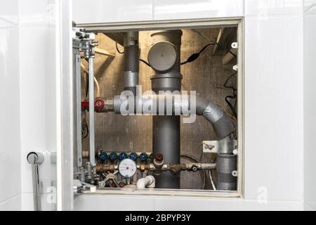 Schalten Sie heißes Wasser. Sanitär-Schrank. Wasserzähler, Kollektor, Wasserdrucksensor Stockfoto