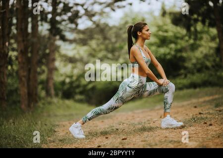 Hübsche junge Frau Stretching und atmen frische Luft in der Mitte des Waldes beim Training Stockfoto