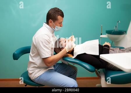 Junge Frau kam zum Zahnarzt zur Untersuchung. Der Zahnarzt Arzt untersucht die Patientenansicht Stockfoto