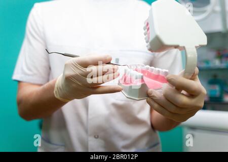 Der Arzt gibt Empfehlungen und zeigt dem Patienten das Verfahren für die zahnärztliche Behandlung am Kiefermodell. Stockfoto