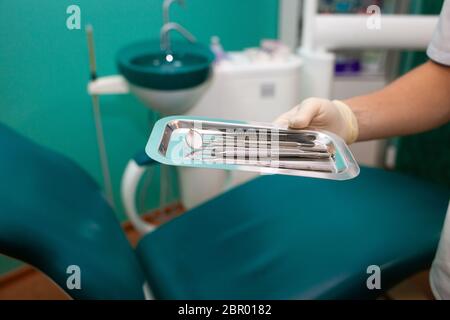 Der Zahnarzt hält viele zahnärztliche Instrumente in den Händen. Sterile zahnärztliche Instrumente aus der Nähe Stockfoto