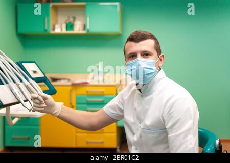 Zahnarzt in einer Maske nimmt einen Bohrer Stockfoto